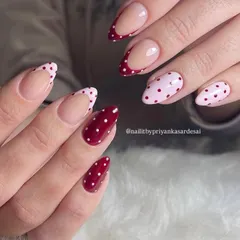 Spotted: the cutest nails in town. This lovely set features a mix of deep red nails and polka-dotted French tips for a fun and classic look.