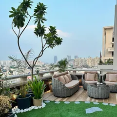 The complete seating arrangement on the rooftop terrace. The combination of a large tree, potted plants, and soft turf creates a garden-like feel high above the urban bustle.