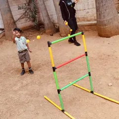 A young boy practices his aim with a ladder toss game outdoors. This activity is great for improving throwing technique and understanding trajectory in a playful context.