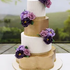 I love creating grand wedding cakes like this four-tiered masterpiece. It features alternating white stencil tiers and metallic gold tiers, all brought together with beautiful handmade sugar flowers in shades of lilac and purple.
