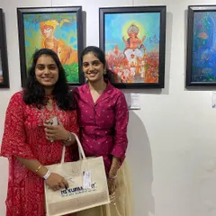 Two students posing with their artwork and an NS Kumbar Art tote bag at the exhibition.