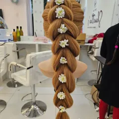 A stunning pull-through braid decorated with small white flowers, created on a mannequin during a practice session.