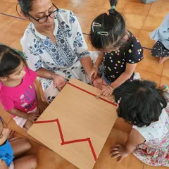 A teacher guides children in a sensorial activity during summer camp. We continue our hands-on learning approach with fun, summer-themed projects.
