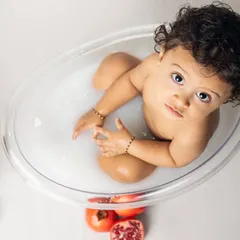 A curious look from the tub. This overhead shot captures a sweet, inquisitive moment during a fun and fruity milk bath photoshoot.