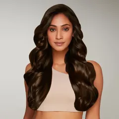 A studio portrait for BBlunt, showcasing perfectly styled, long wavy hair. This image is a key visual used in packaging and advertising, focusing entirely on the aspirational result of using the brand's hair products.