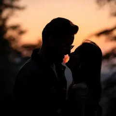A close-up silhouette of a near-kiss, capturing the anticipation and intimacy of the moment against the soft colors of the sunset.