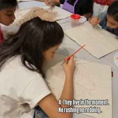 Kids live in the moment. There's no rushing, no redoing, just pure focus on the task at hand. Here, a group of girls is intently painting designs on canvas tote bags.