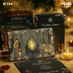 This is a premium boxed invitation designed for a grand wedding. The dark, elegant background makes the gold foil illustrations of the couple, wedding canopy, and elephants stand out. The intricate detailing makes it a true statement piece.