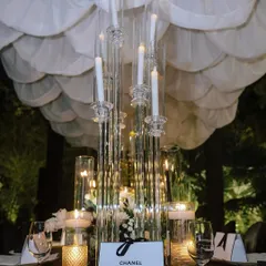 A Chanel-inspired tablescape, featuring tall, modern candelabras, a custom "Chanel" favor box, and a scalloped white ceiling drape.