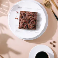 A top-down view of a fudgy brownie paired with a cup of black coffee. This classic pairing is styled with clean lines and contrasting colors to create a modern and sophisticated look for a cafe or dessert brand.