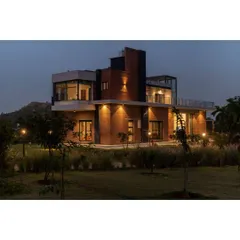 The Nandi Hills residence illuminated at dusk. We used strategic architectural lighting to highlight the building's form and warm brick texture, creating an inviting glow that integrates the home into its natural, grassy surroundings.