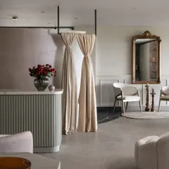 Another angle of our reception area, highlighting the interplay between the soft, patterned drapes and the clean lines of the custom-made chairs. The ornate gold mirror adds a touch of classic luxury against the neutral, paneled walls.