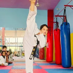 A demonstration of pure flexibility and technique. This student is executing a perfect vertical high kick, a fundamental skill in Taekwondo that requires immense practice and control.