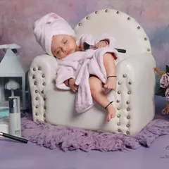 A 'Mini Spa Day' for the tiniest client. This humorous and adorable theme features a baby in a tiny bathrobe and towel, hilariously "passed out" in a miniature armchair after a relaxing "treatment."