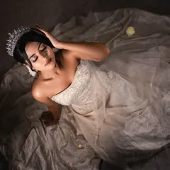 An artistic, top-down shot of the bride in her gown. The dramatic lighting highlights the delicate texture of the dress and the regal tiara.