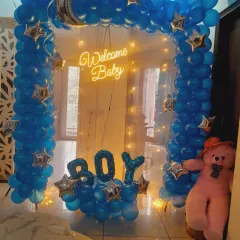 A closer look at the "Welcome Baby Boy" balloon arch, showing the teddy bear and fairy light details.