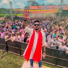 Waving to the incredible crowd at a Holi festival. Dressed in traditional white and red, I was right in the middle of the celebration, leading the party from the stage.