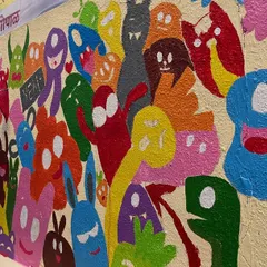 The process of filling in the doodle mural, showing how each monster is individually painted to create a dense and energetic composition.