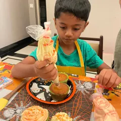 The concentration is real. This young baker is mastering the art of piping frosting onto his Halloween-themed cupcakes, all made from scratch.