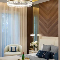 This master bedroom is a testament to refined relaxation. We designed a feature wall with chevron-patterned wood paneling to add warmth and texture. The space is crowned by a stunning crystal ring chandelier, creating an ambiance of pure elegance and comfort.