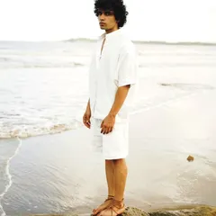 A male model portfolio shot at Versova beach. The composition uses a rock to create a strong pose, with the open sea providing a clean, natural background.