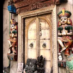 An intricately carved traditional Indian door, flanked by colorful statues. We draw immense inspiration from such historical craftsmanship, often incorporating vintage or custom-made pieces to add soul to modern interiors.