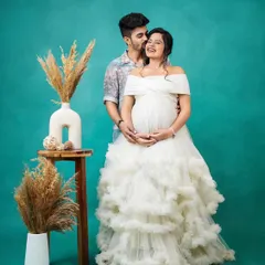 A joyful moment captured in the studio. This couple looks picture-perfect, with her in a stunning white off-the-shoulder ruffled gown and him in a complementary casual shirt.