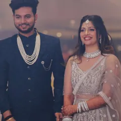 A beautiful couple ready for their engagement. The bride's soft glam makeup with loose curls complements her intricate silver lehenga.