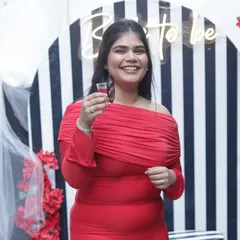 The bride-to-be, radiant in red, raising a toast to her upcoming wedding.