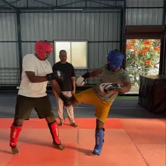 Two students sparring under my supervision. They are practicing their kicks and blocks, learning to read an opponent's movements and react effectively.