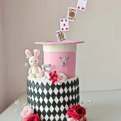 A sprinkle of magic for a special birthday. This two-tier cake features an anti-gravity illusion with playing cards floating out of a magician's hat, complete with a cute fondant bunny and fresh flowers for a spellbinding surprise.
