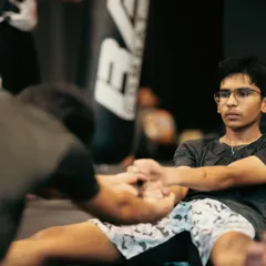 Flexibility is key to preventing injuries and executing techniques like high kicks. Here, a student works on a seated stretch with assistance to improve his range of motion.