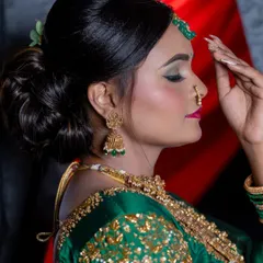 A side profile of a green lehenga look, showing off the elegant bun hairstyle and shimmering eye makeup.