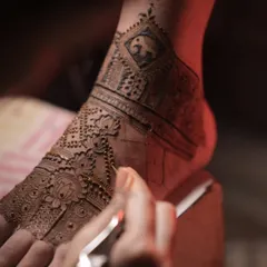 Another view of the bridal foot mehendi, showing the combination of the elephant band and a delicate lotus pattern being drawn on the top of the foot.
