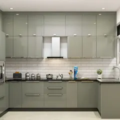 This sage green kitchen showcases a full wall of floor-to-ceiling cabinets, offering immense storage. The U-shaped layout and stainless steel handles give it a professional and highly functional feel.
