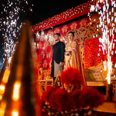 A dramatic couple entry for a royal-themed reception. We used cold pyro fireworks to frame the couple on stage, creating a spectacular and unforgettable moment against a backdrop of red florals and intricate gold patterns.