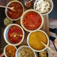 This is what a feast looks like at my place. Multiple bowls of different curries like pork, chicken, and dal, along with freshly steamed momos, ready for a large gathering.
