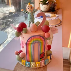 A fun Cocomelon-themed cake for little Isabelle's second birthday. This fresh cream cake is decorated with a colorful rainbow, playful spheres, and a cute fondant character topper.
