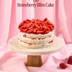 The Strawberry Bliss Cake, presented on a marble stand. It's one of our seasonal bestsellers, known for its light texture and generous strawberry topping.