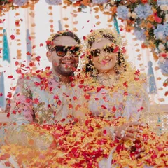 A shower of red and yellow petals rains down on the happy couple during their vibrant Haldi ceremony in Rajasthan.