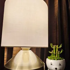 This small, quirky pot is designed to look like a cute animal face. It's a playful addition to any room and is shown here holding a small plant, perfect for a bedside table or a child's room.