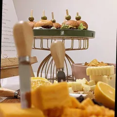 A close-up view of a cheese board, showcasing a variety of textures from creamy to crumbly, paired with mini burgers in the background. It's all about offering delightful contrasts.
