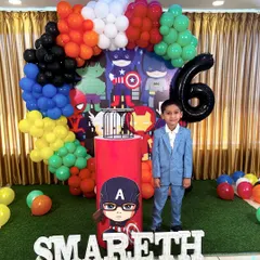 A full Avengers-themed birthday setup for a 6th birthday. The backdrop features multiple superheroes, surrounded by a colorful balloon arrangement and a large number '6' balloon.