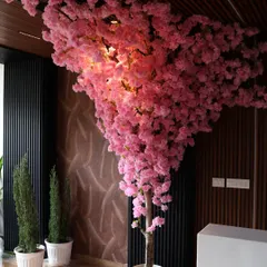 An artificial Cherry Blossom tree adds a dramatic pop of color and elegance to this modern interior. Our custom trees are perfect for creating a unique and memorable ambiance in any space.