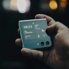 A lifestyle product shot of the Samsung Galaxy Z Flip 5. I focus on capturing the device in real-world scenarios, highlighting its design and user interface against an atmospheric, out-of-focus city background.