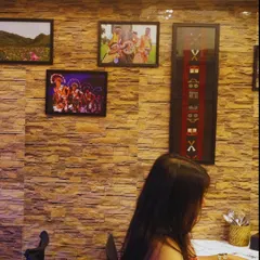 A guest enjoying her meal. In the background, you can see our wall decorated with photos and textiles from the Northeast, which adds to the authentic atmosphere.