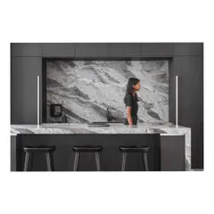 A wider view of the kitchen and bar, showcasing the dark wood cabinetry that provides a beautiful contrast to the veined stone.