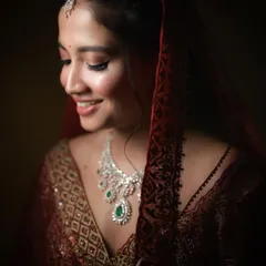 A close-up of the same bride, this time with a soft smile. This portrait showcases her beautiful jewelry and the delicate details of her wedding attire under soft, flattering light.