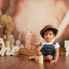 A first birthday milestone shoot with a "One" sign and a rustic, boho-themed backdrop. This studio setup is perfect for celebrating that big first year.