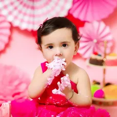 A close-up of a baby girl enjoying her cake smash, with pink frosting all over her hands and face. These messy moments are the most fun to capture.